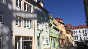 A row of colorful buildings with large windows and a cobblestone street. - Stella Apartments (Erfurt)