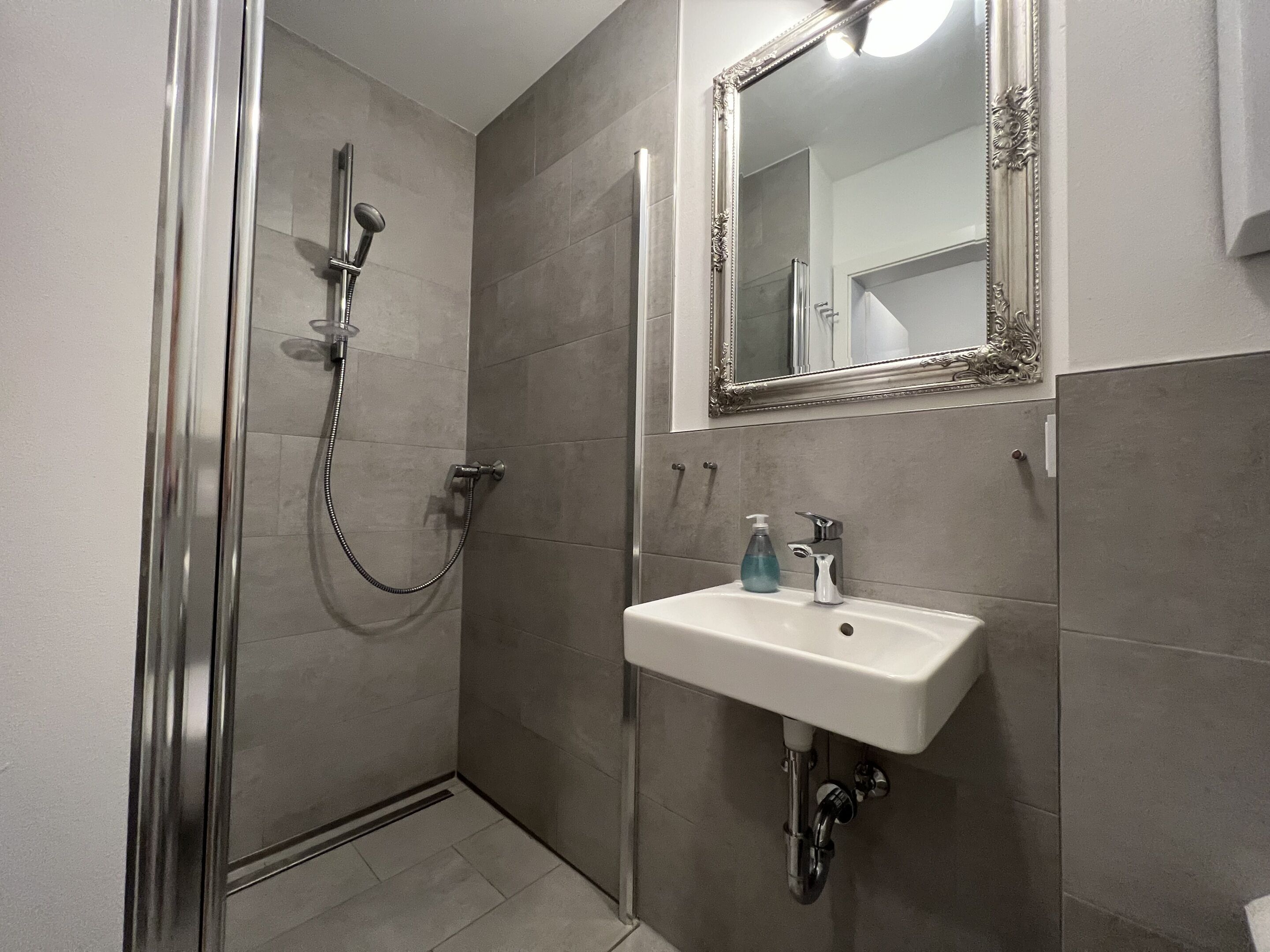 Un baño con ducha, lavabo y espejo.