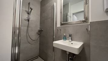 Un baño con ducha, lavabo y espejo.