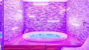 A modern bathroom with a wooden floor, a circular hot tub, and a pink chair. - Kyriad Prestige Hôtel and Spa, Amiens Nord (Poulainville)