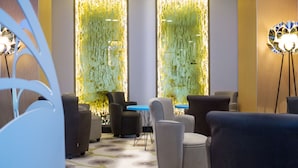 A modern lounge area with sofas and tables, decorative panels, and ambient lighting. - Kyriad Prestige Hôtel and Spa, Amiens Nord (Poulainville)