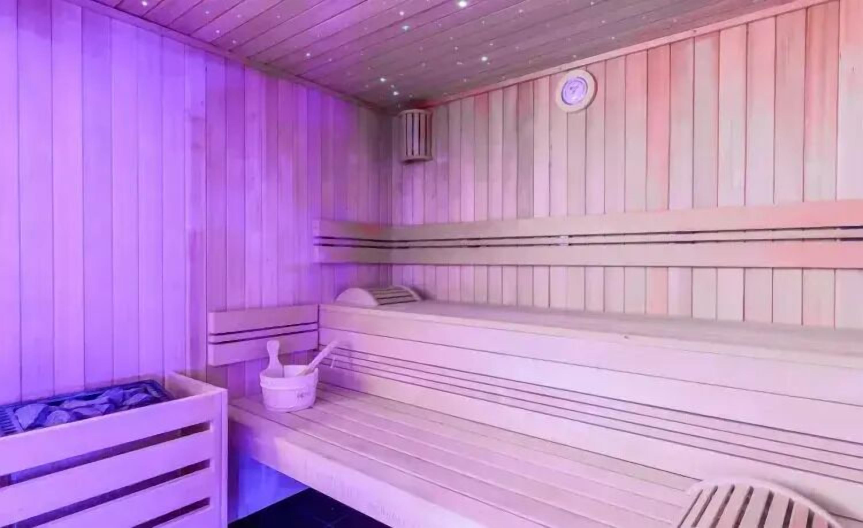 A sauna with wooden benches and a small table with a bucket and brush.