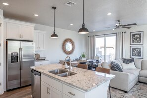 Una cocina moderna con refrigerador de acero inoxidable, encimera de granito e iluminación colgante.