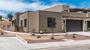 A modern house with a garage, stone accents, and a landscaped front yard. - The Perfect Escape (St. George)