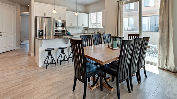 A modern kitchen with a central island, dining area with chairs, and a large window with curtains. - The Perfect Escape (St. George)