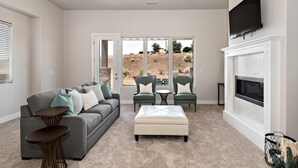 A living room with a gray sofa, two green armchairs, a small round table, and a white ottoman. - The Perfect Escape (St. George)