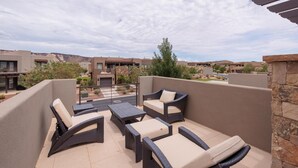 A rooftop patio with wicker furniture, a view of the surrounding buildings, and a clear sky. - Suite Escapes (St. George)