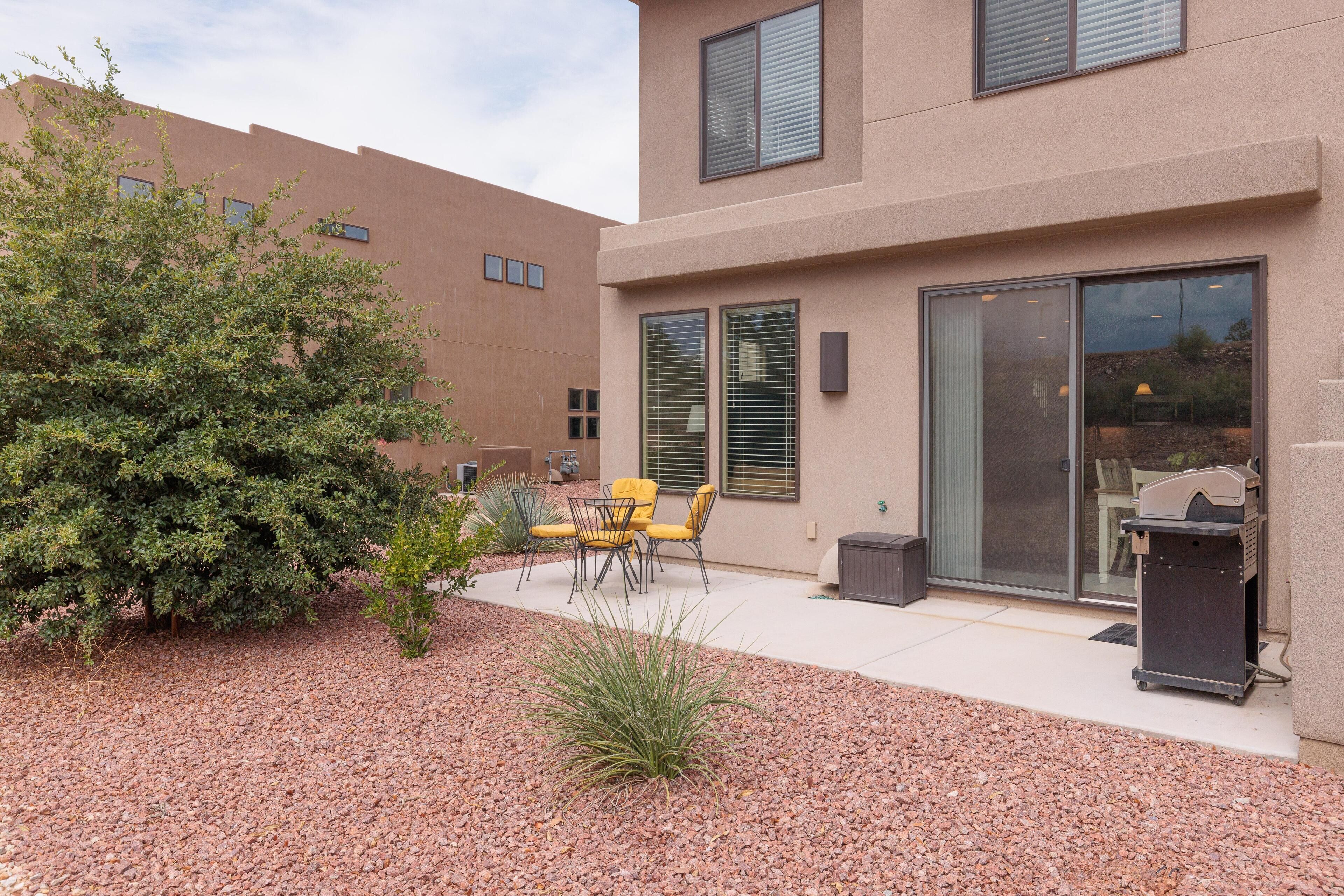 A modern building with a patio area featuring outdoor furniture and a small garden.
