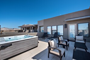 Une terrasse sur le toit dotée d’un jacuzzi, de coins salon extérieurs et de grandes fenêtres offrant une vue sur la ville.
