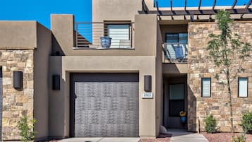 A modern two-story house with a stone facade, a garage, and a balcony with outdoor furniture.