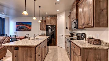 A spacious kitchen with granite countertops, wooden cabinets, and pendant lighting.