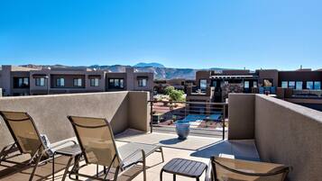 A rooftop terrace with outdoor seating, a pool, and mountain views.