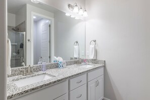 A bathroom with a granite countertop, two sinks, a mirror, and a shower area. - 18 Holes and A Hot Tub (St. George)