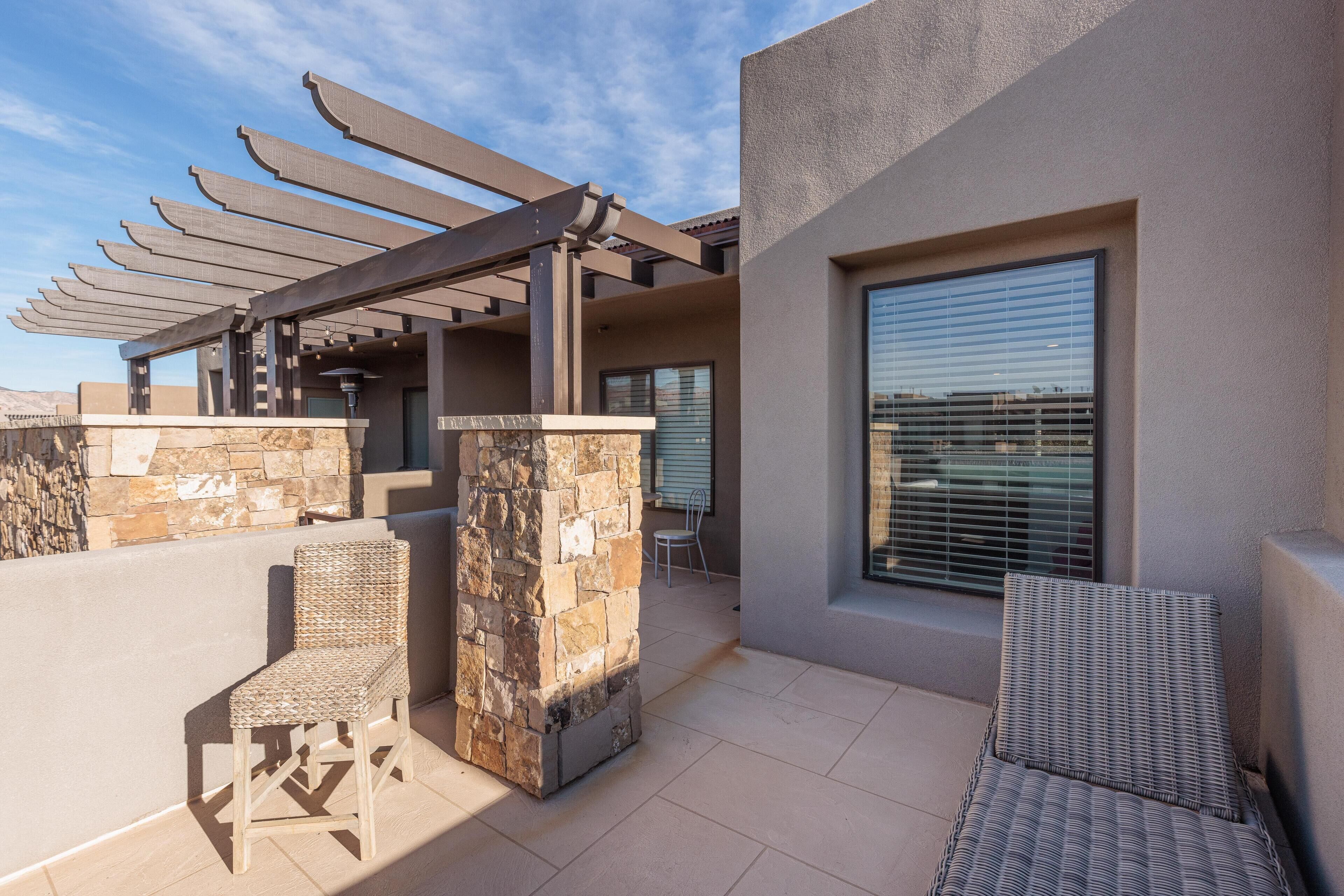 A patio area with wicker furniture, a pergola, and a stone pillar.