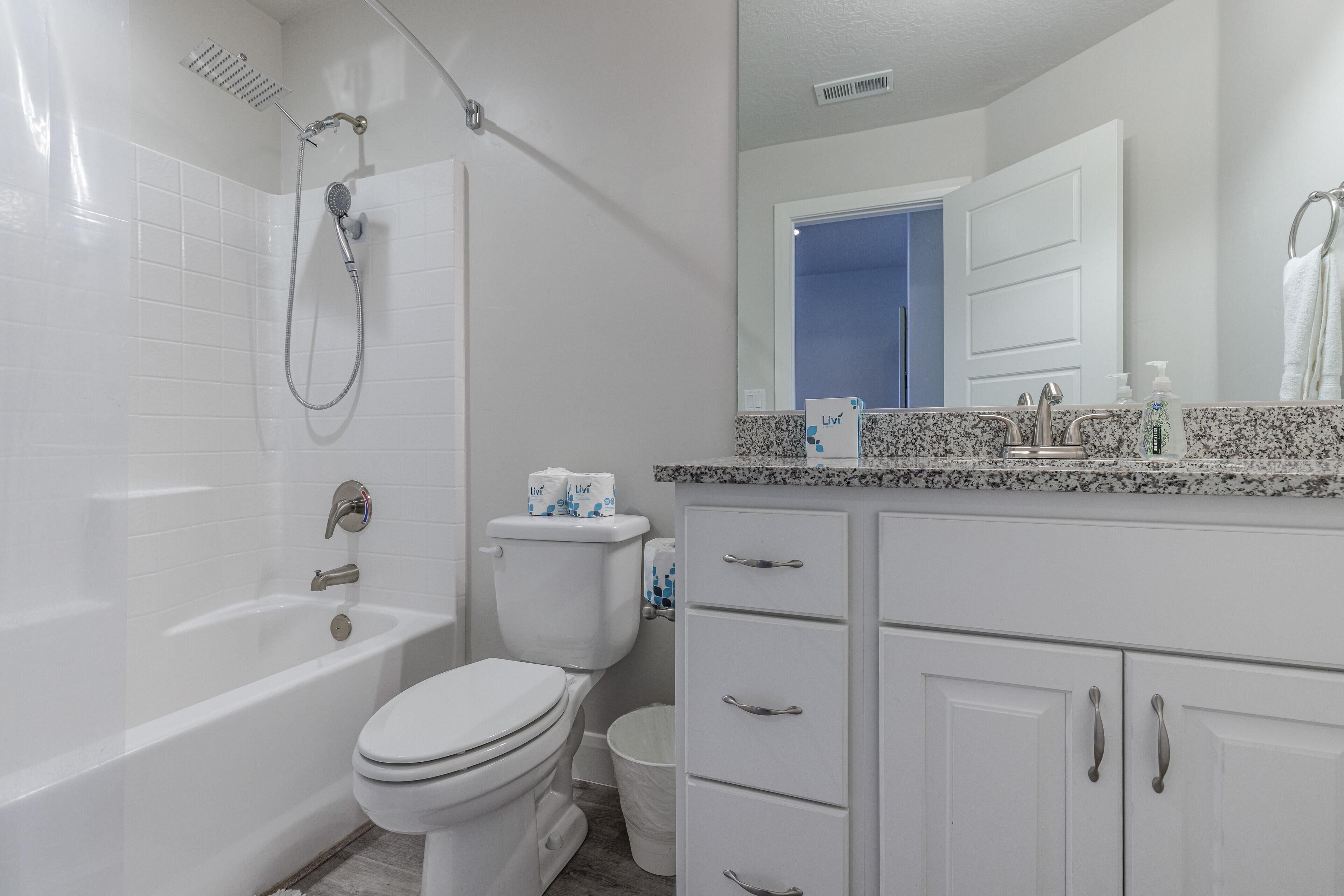 Un bagno moderno con vasca, servizi igienici e un mobile lavabo con specchio.