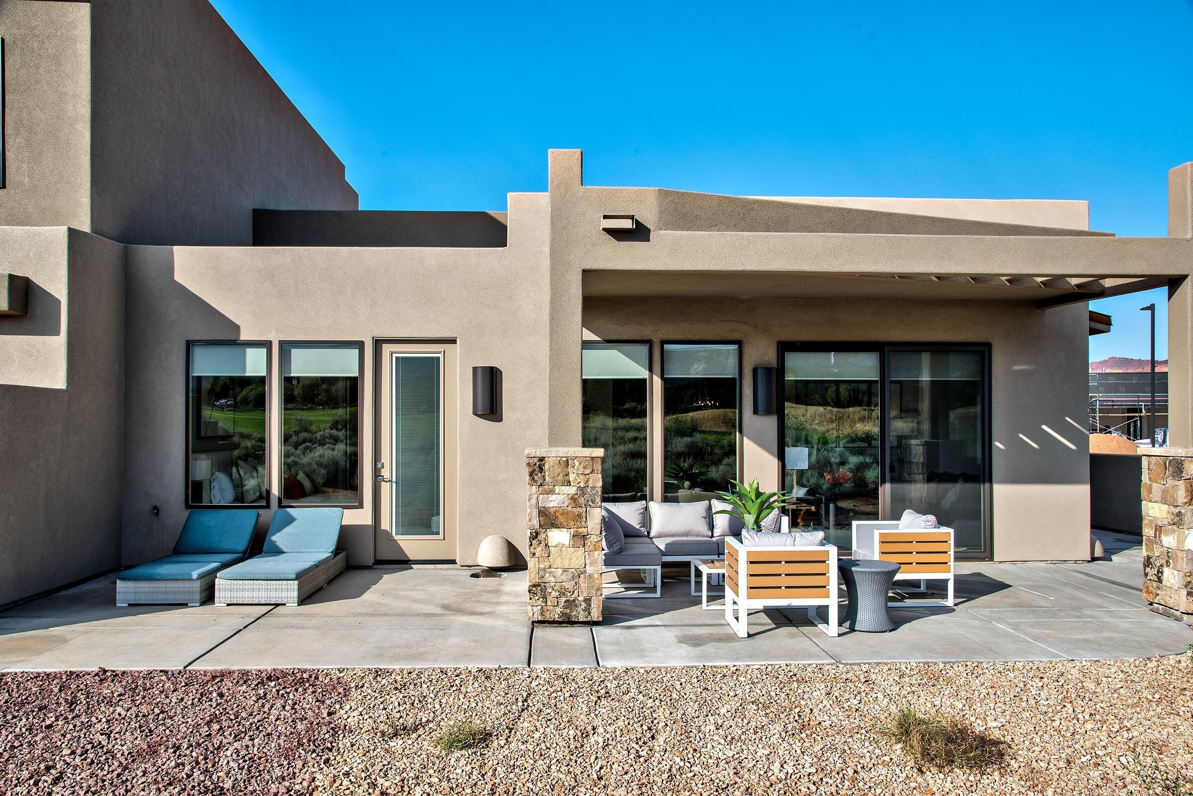 A modern house with a patio, outdoor seating, and large windows.