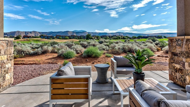An outdoor patio with seating, a potted plant, and a view of a desert landscape with mountains in the background. - Villa On The 18th (St. George)