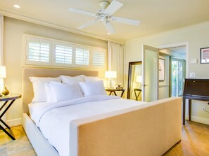 A hotel room with a large bed, a ceiling fan, a piano, and a door leading to a balcony.