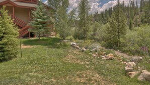 Eine Lodge mit Holzausbau, einer Treppe und einem Garten mit verschiedenen Pflanzen und Steinen.