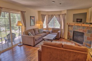 A living room with a fireplace, a sofa set, and a television mounted above it. - Villas at Swan's Nest #701 (Condo) Apartment 2 (Breckenridge)