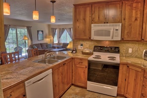 A kitchen with wooden cabinets, a microwave, a stove, and a dishwasher.