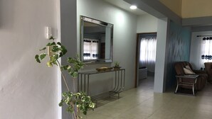 A living room with a potted plant, a sofa, a coffee table, and a TV. - Ladyville 2Bed 2Bath (Ladyville)