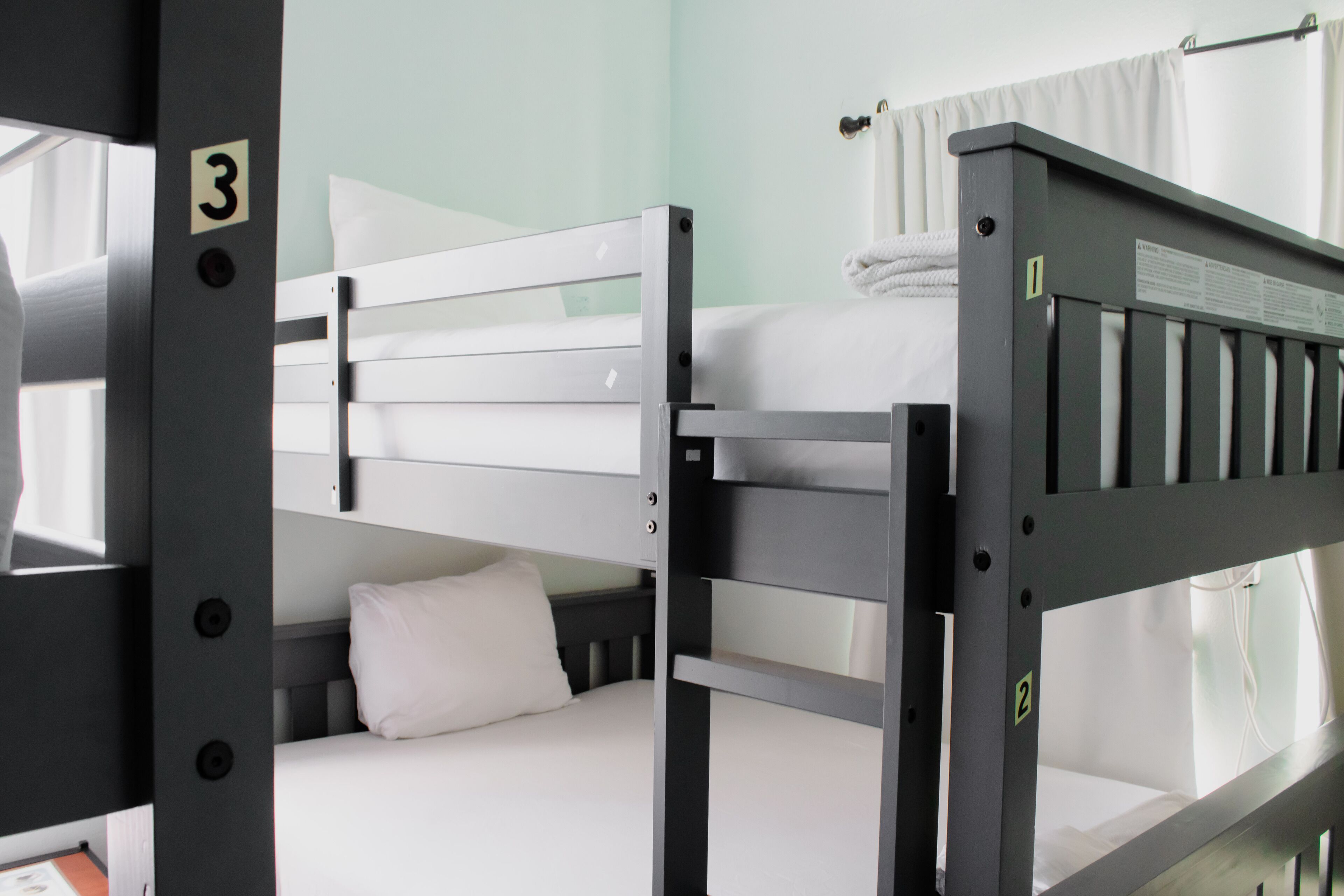A bunk bed with a white mattress and pillow, a metal frame, and a number '3' sign.