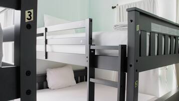 A bunk bed with a white mattress and pillow, a metal frame, and a number '3' sign.