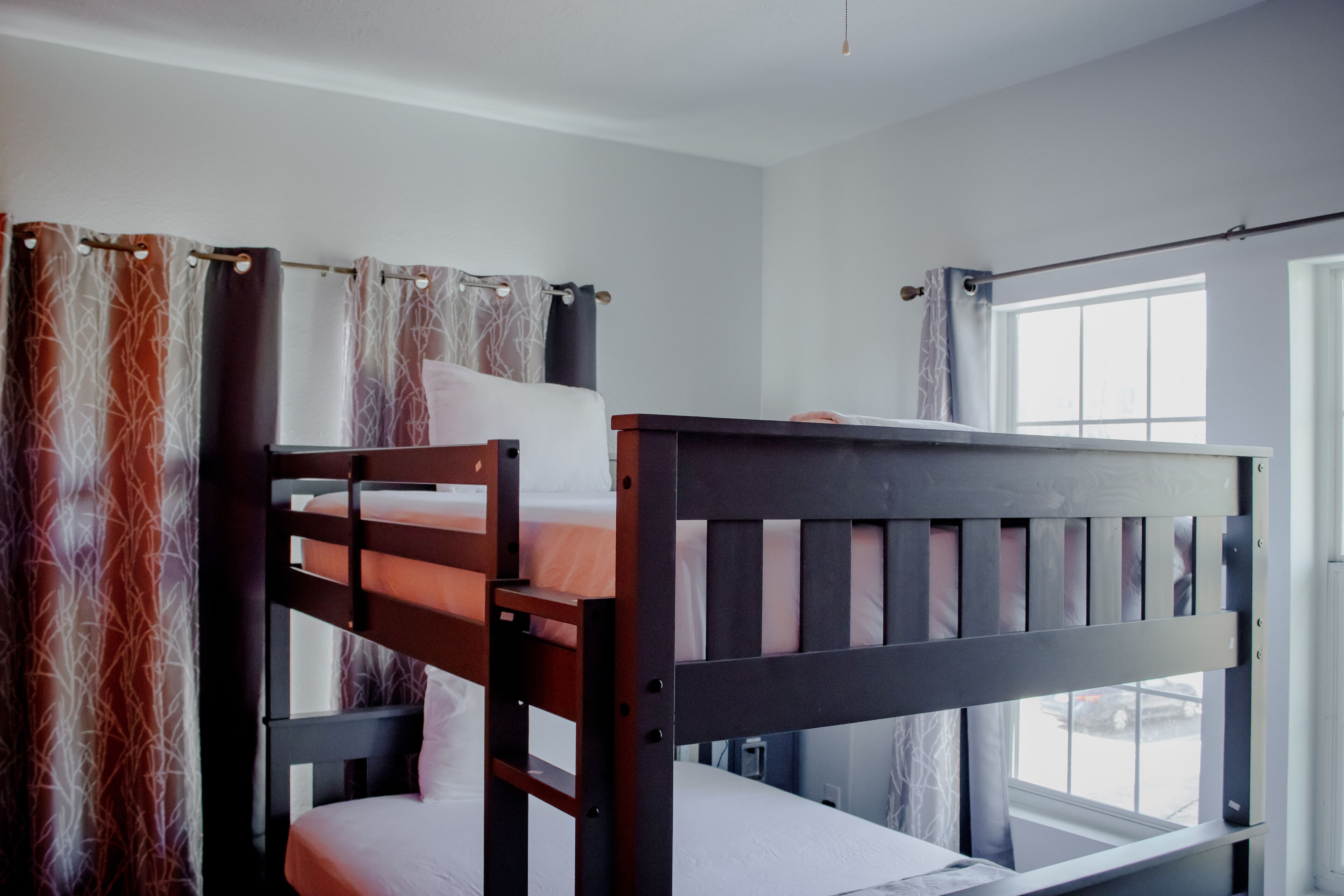 A bunk bed in a room with a window and curtains.