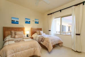 A hotel room with two beds, a ceiling fan, and a large window with curtains. - Condo Complex with an Alluring Pool & Tropical Vibes by Stella Rentals (Tulum)