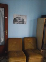 A room with a blue wall, a door with a curtain, and two brown sofas.