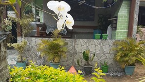 A building with a tiled roof, stone walls, and potted plants. - Pousada Japariz (Angra dos Reis)