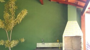 An outdoor kitchen area with a green wall, a potted plant, and a brick oven. - Pousada Japariz (Angra dos Reis)