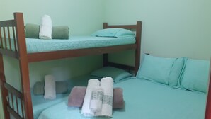 A bunk bed room with a green bedspread, pillows, and rolled towels. - Pousada Japariz (Angra dos Reis)