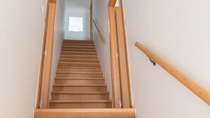 Una escalera de madera con barandilla que conduce a un rellano con una puerta.