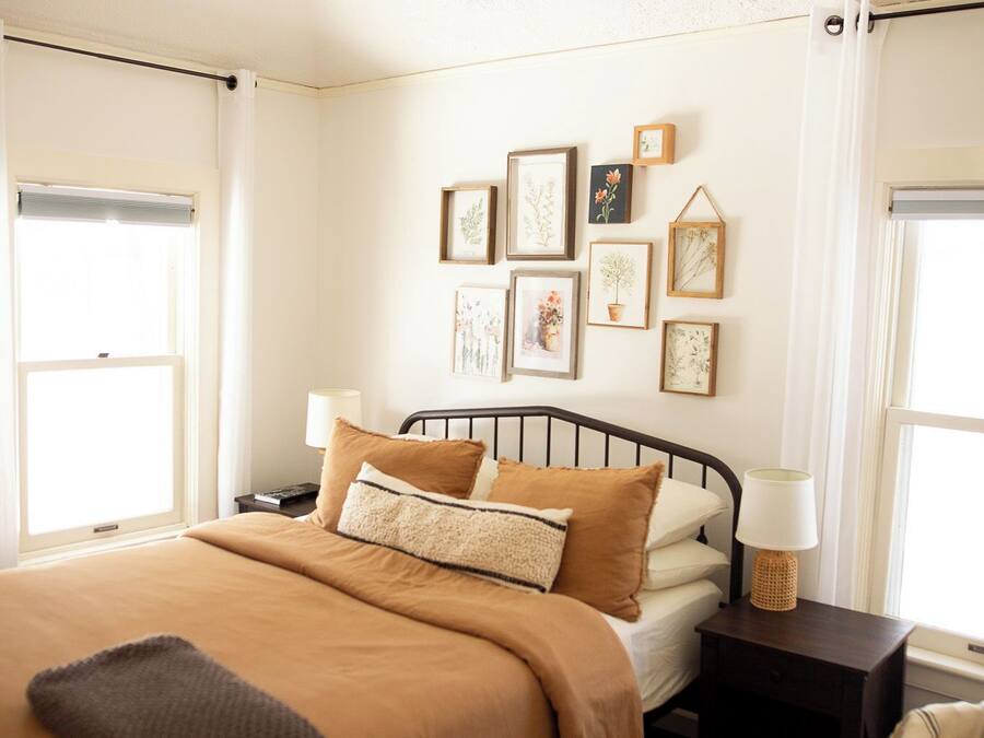 Un dormitorio con cama, mesitas de noche, una obra de arte en la pared y una lámpara en el techo.