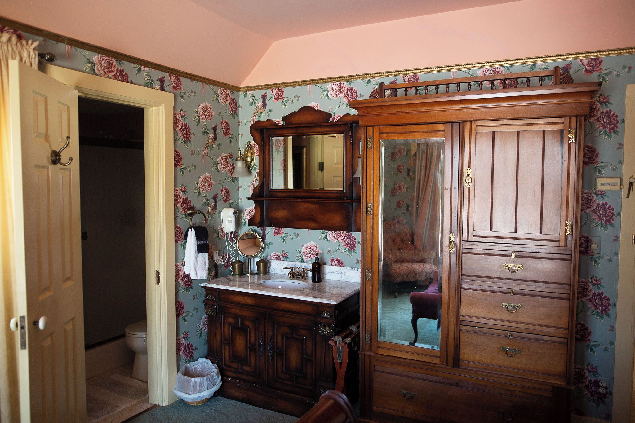 A bathroom with a wooden vanity, a mirror, and a cabinet.
