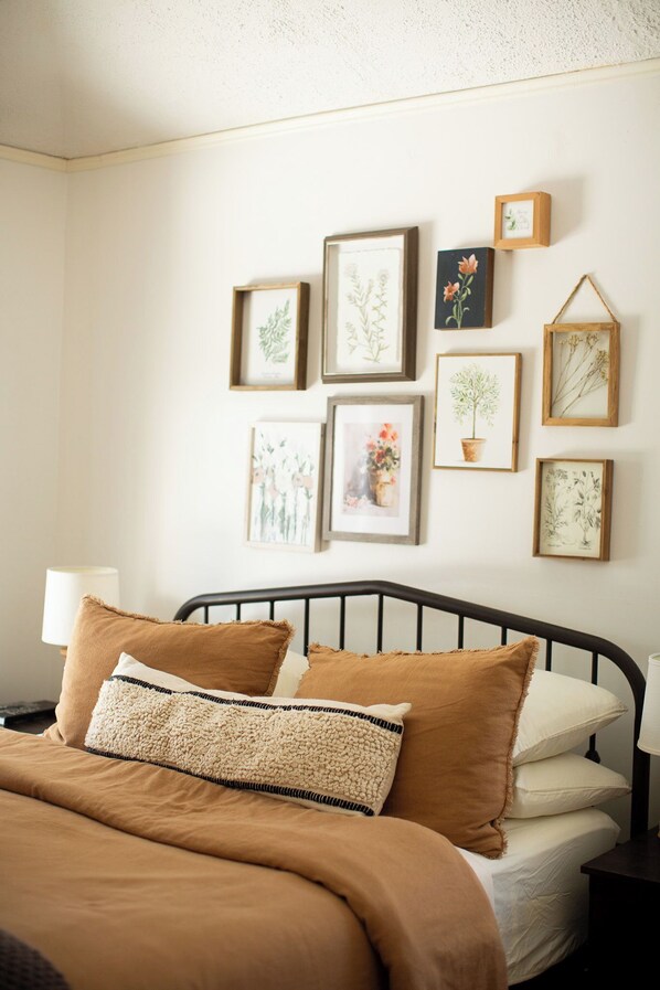 A bedroom with a bed, pillows, and a wall decorated with framed botanical prints. - The Park Street Inn (Bellaire)