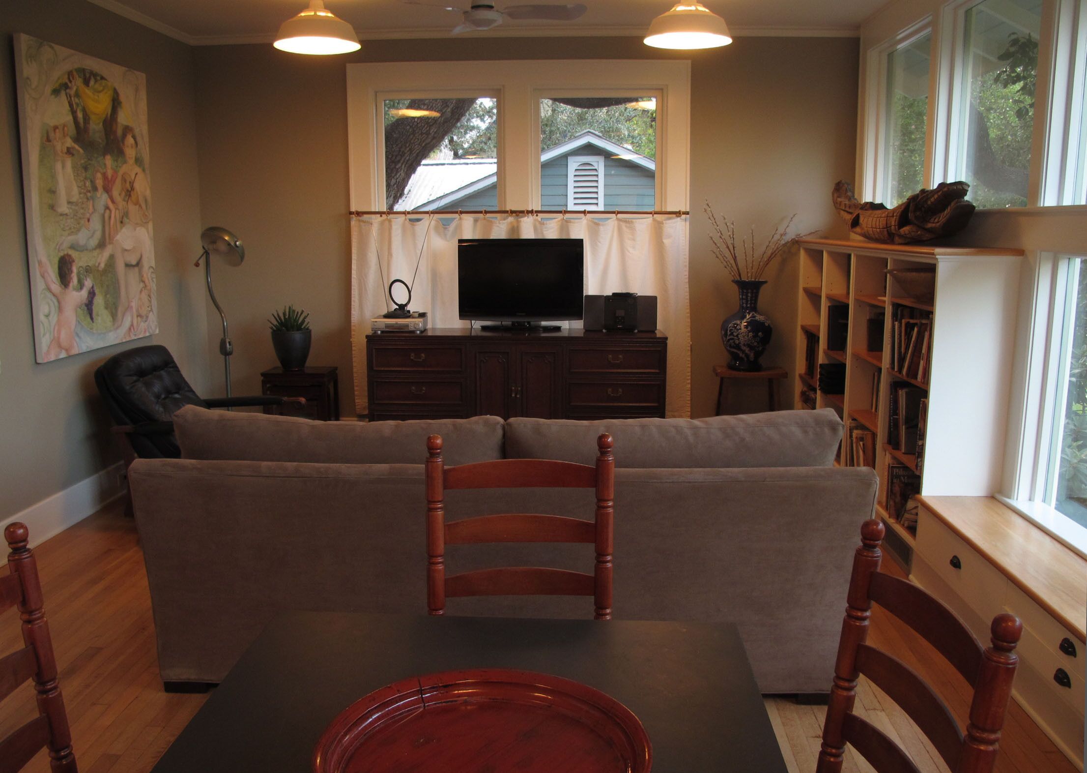 Una sala de estar con un sofá, una televisión, una estantería y una mesa de comedor con sillas.
