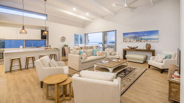 A spacious living area with a kitchen, a dining area, and a large window offering a view of the cityscape. - Superb Dual Keyed Home with Stunning Ocean Views just 300 Metres to Beach (Dunsborough)