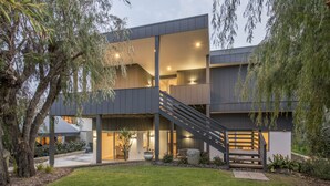A modern two-story house with a staircase leading to the upper floor, surrounded by greenery and trees. - Superb Dual Keyed Home with Stunning Ocean Views just 300 Metres to Beach (Dunsborough)