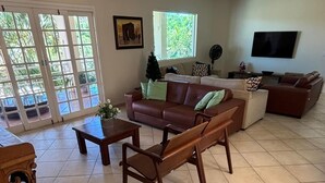 Una sala de estar con un sofá de cuero marrón, una mesa de centro de madera y un televisor en la pared.