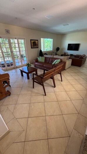A living room with a brown leather sofa, a wooden coffee table, and a TV on the wall. - COUNTRY HOUSE (10 suites) W/AR, POOL, ETC. (Boituva)