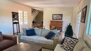 Una sala de estar con sofá, sillón, mesa de centro y un pequeño árbol de Navidad.