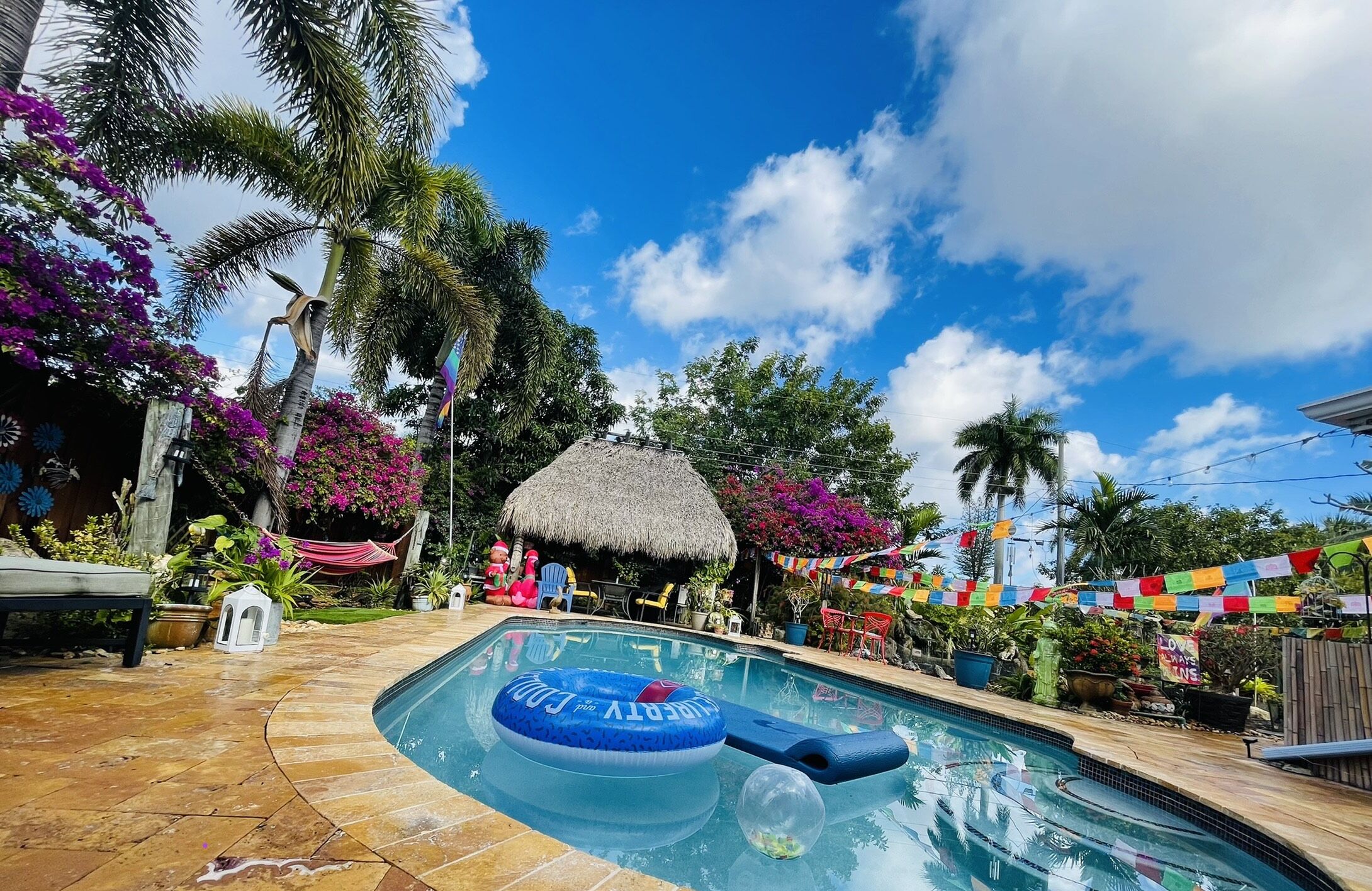 A swimming pool with a blue inflatable ring, surrounded by palm trees and colorful decorations.