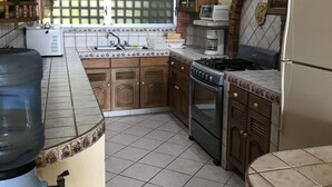 A kitchen with tiled flooring, wooden cabinets, a gas stove, and a refrigerator.