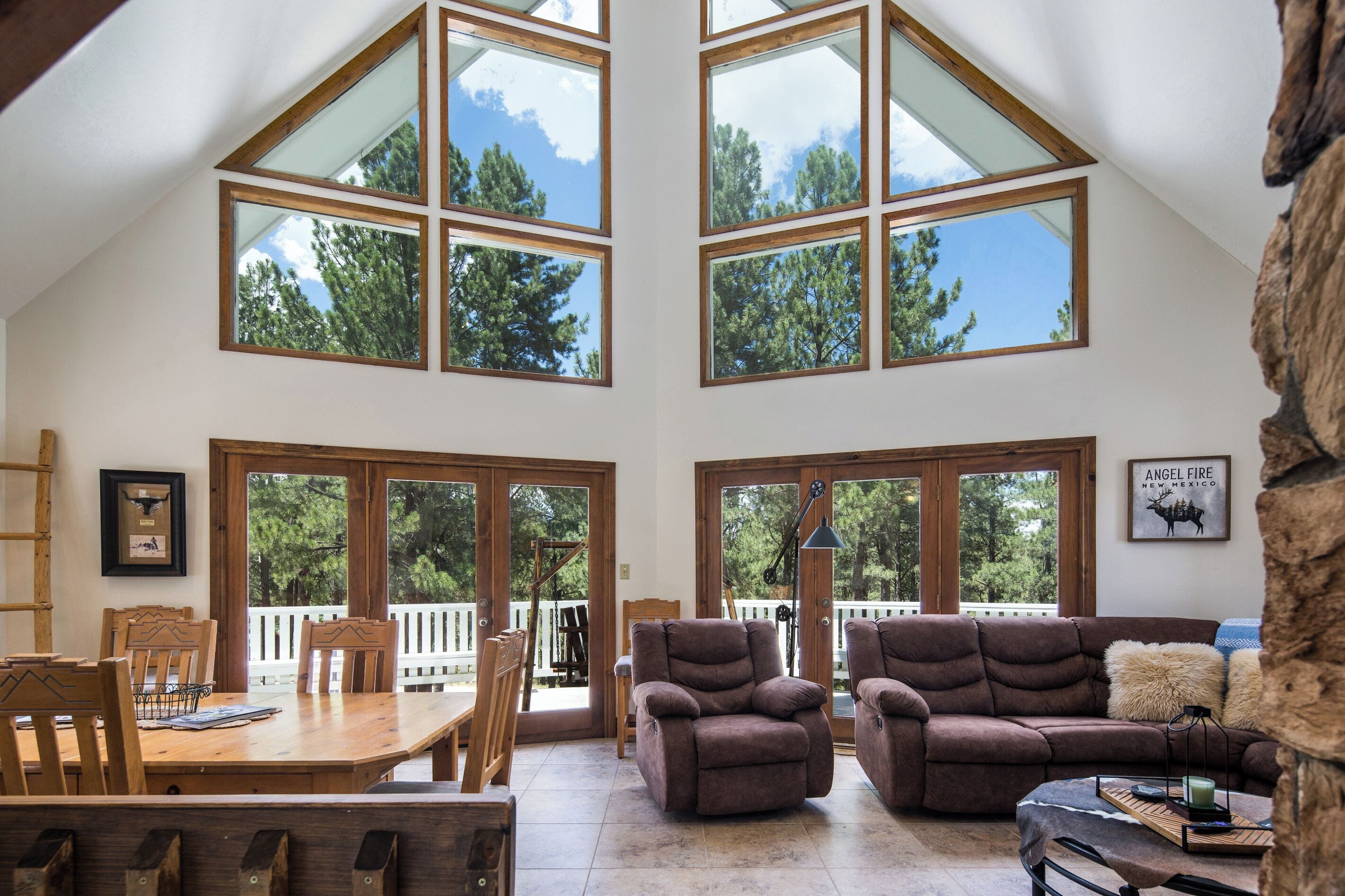 A spacious loft with high ceilings and large windows offering views of trees.