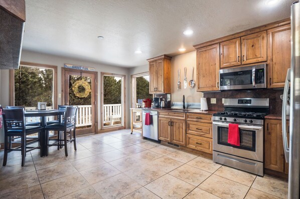 A spacious kitchen with wooden cabinets, stainless steel appliances, and a dining area with a view of the outdoors.