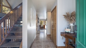 A hallway with a wooden staircase, a dining area, and a green door. - Newly Updated Mtn House! Walk to Golf/Tennis/Park, Hot Tub, Firepit, Ping Pong (Angel Fire)