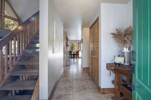 A hallway with a wooden staircase, a dining area, and a green door.